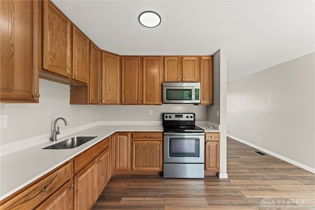 1927 Vermont Dr, Xenia, OH 45385 - kitchen with appliances with stainless steel finishes, light countertops, brown cabinets, and wood finished floors