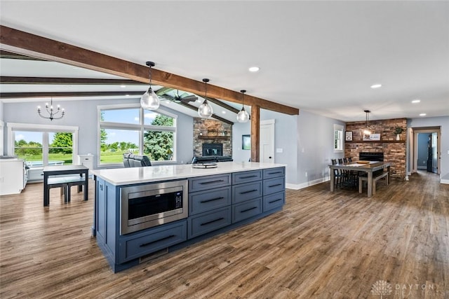 1737 Wilmington Rd, Cedarville Twp, OH 45314 - kitchen with stainless steel microwave, a large fireplace, dark wood-style floors, light countertops, and pendant lighting