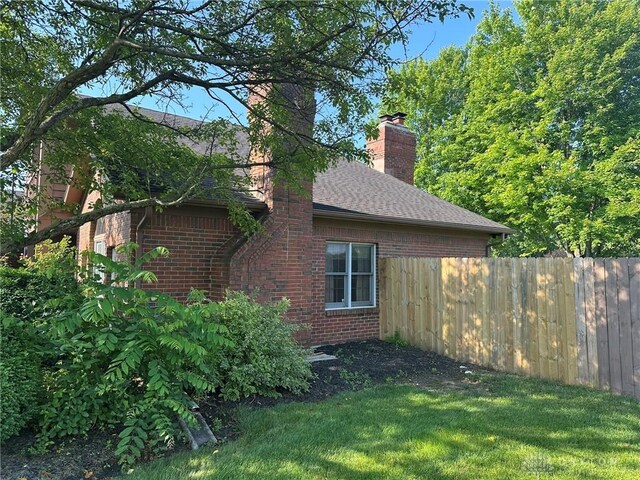 6553 Stillcrest Way, Dayton, OH 45414 - view of home's exterior with brick siding, a chimney, and roof with shingles