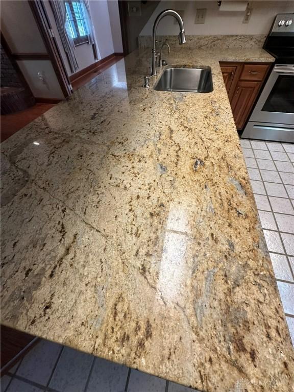6553 Stillcrest Way, Dayton, OH 45414 - kitchen with stainless steel range with electric stovetop, brown cabinetry, and light stone countertops