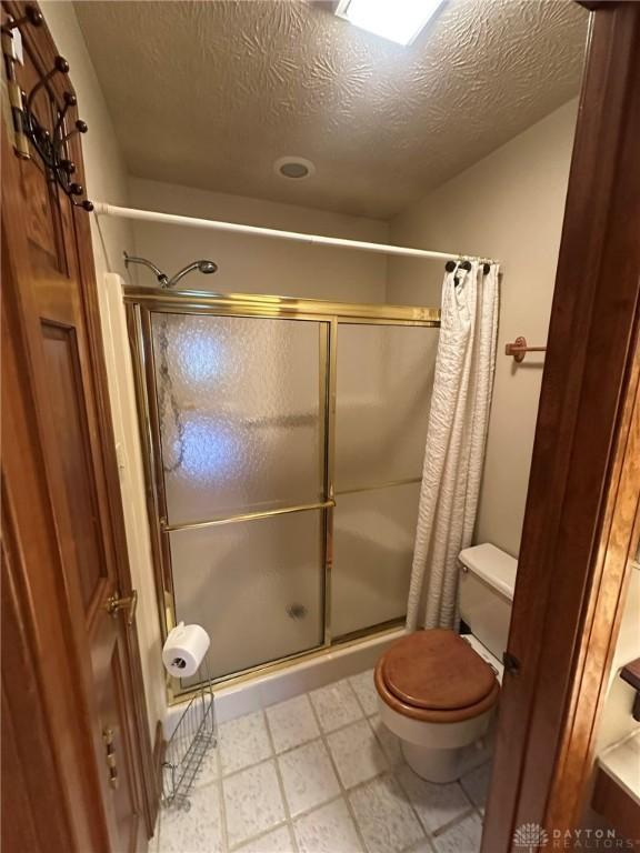 6553 Stillcrest Way, Dayton, OH 45414 - bathroom featuring a stall shower, a textured ceiling, and tile patterned floors