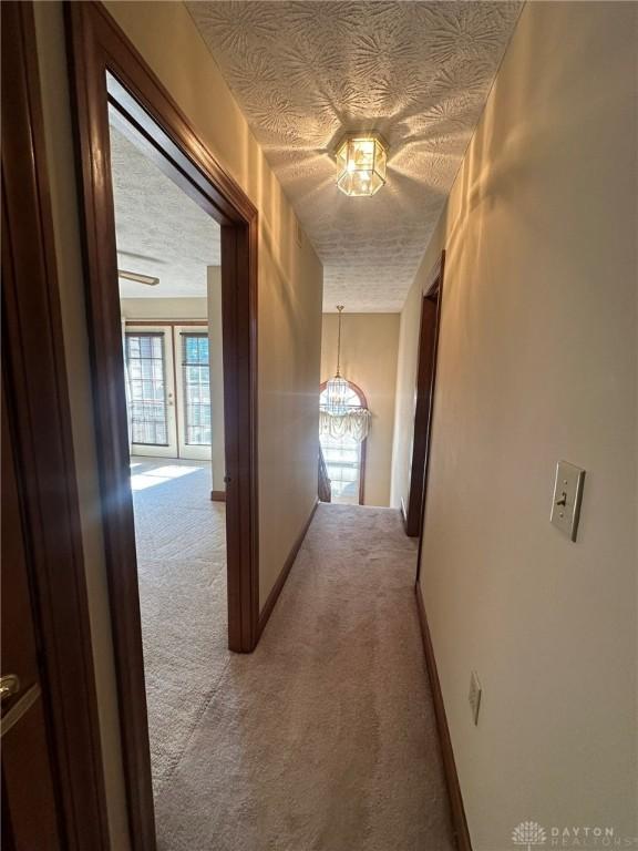 6553 Stillcrest Way, Dayton, OH 45414 - hall with light carpet, a textured ceiling, and a chandelier
