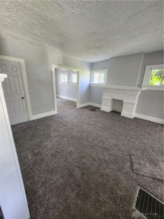953 Five Oaks Ave Unit 943, Dayton, OH 45406 - unfurnished living room with a textured ceiling, carpet floors, and a brick fireplace