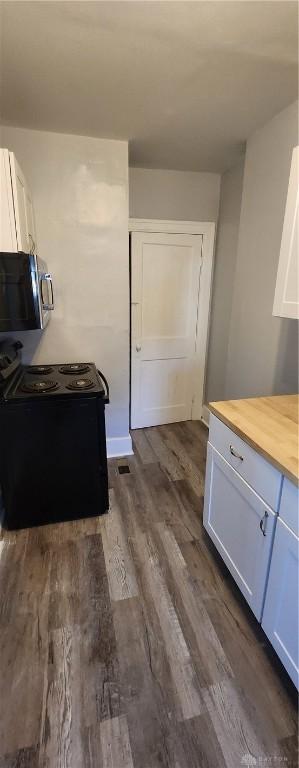 953 Five Oaks Ave Unit 943, Dayton, OH 45406 - kitchen with stainless steel microwave, black range with electric stovetop, wooden counters, dark wood-style floors, and white cabinetry