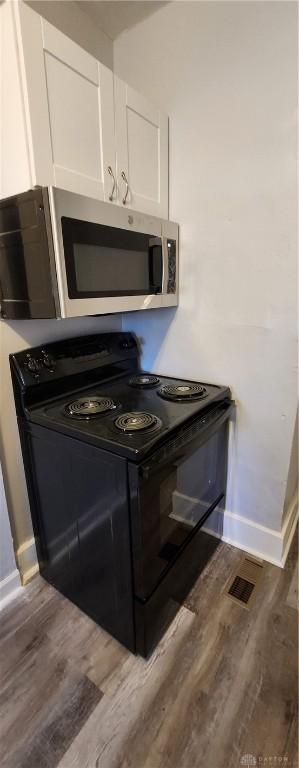 953 Five Oaks Ave Unit 943, Dayton, OH 45406 - kitchen featuring black electric range, stainless steel microwave, white cabinets, and wood finished floors