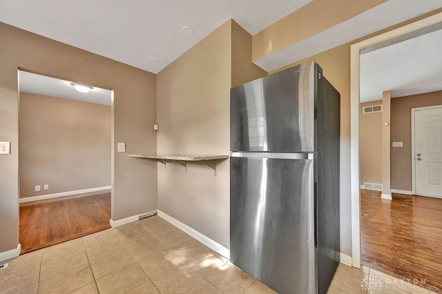 1210 Clovernook Dr, Hamilton, OH 45013 - kitchen featuring freestanding refrigerator, light tile patterned flooring, a kitchen breakfast bar, and light stone counters