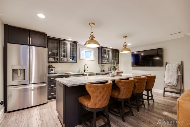 243 Woodside Trl, Clearcreek Twp, OH 45036 - kitchen with stainless steel fridge, a breakfast bar area, light wood-style floors, pendant lighting, and recessed lighting