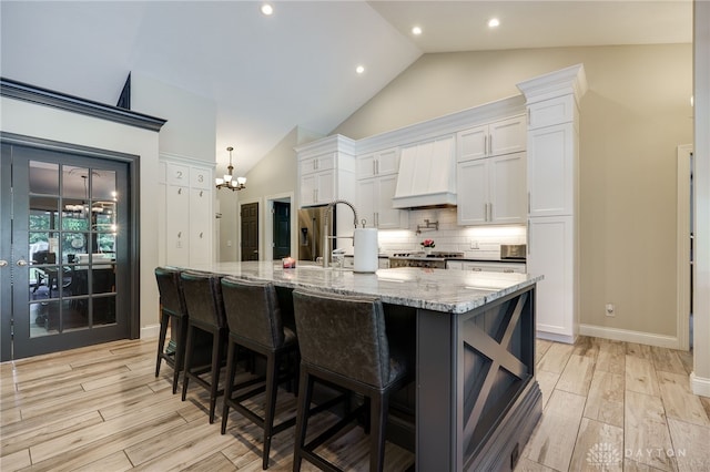243 Woodside Trl, Clearcreek Twp, OH 45036 - kitchen with a chandelier, vaulted ceiling, white cabinets, light wood finished floors, and backsplash
