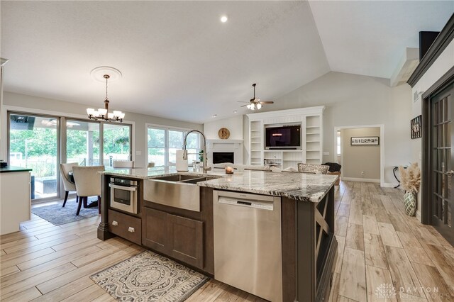 243 Woodside Trl, Clearcreek Twp, OH 45036 - kitchen featuring appliances with stainless steel finishes, light wood finished floors, a fireplace, ceiling fan, and lofted ceiling