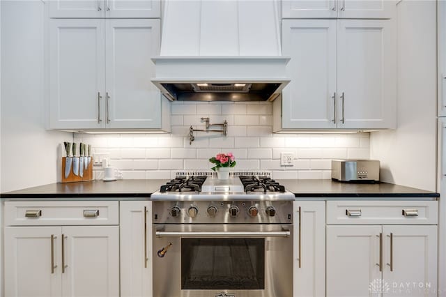 243 Woodside Trl, Clearcreek Twp, OH 45036 - kitchen featuring high end stove, custom range hood, dark countertops, white cabinets, and backsplash