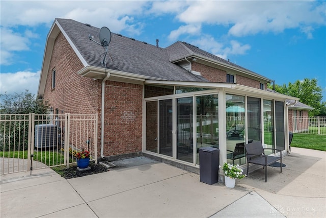 3875 Ferry Rd, Sugarcreek Twp, OH 45305 - rear view of property featuring a sunroom, brick siding, a patio, and a shingled roof