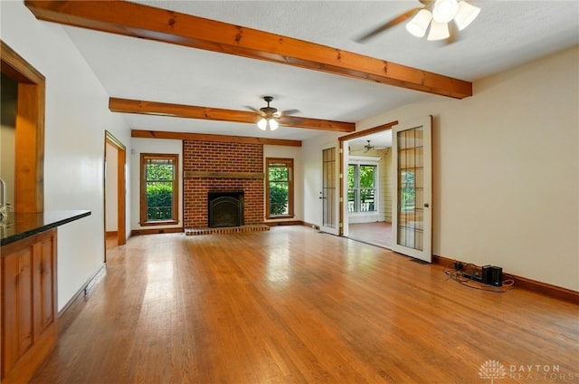 7255 State Route 48, Springboro, OH 45066 - unfurnished living room with a ceiling fan, wood finished floors, beamed ceiling, and a brick fireplace
