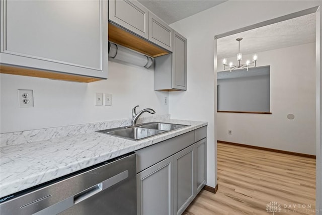 7607 Paragon Commons Cir, Dayton, OH 45459 - kitchen with stainless steel dishwasher, gray cabinets, light countertops, light wood-type flooring, and a chandelier
