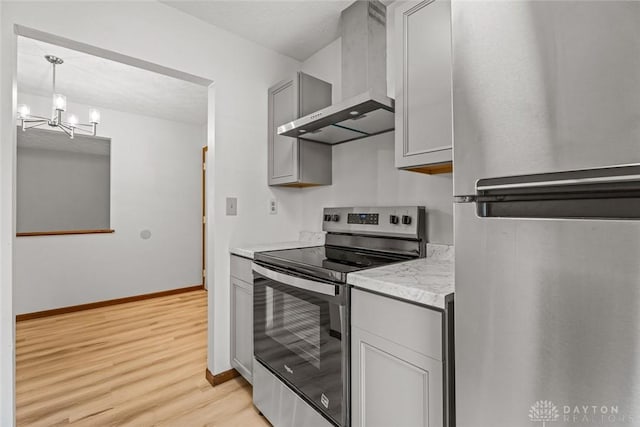 7607 Paragon Commons Cir, Dayton, OH 45459 - kitchen featuring stainless steel appliances, wall chimney exhaust hood, light wood finished floors, a chandelier, and gray cabinets