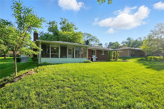 320 Witherby Dr, Kettering, OH 45429 - rear view of house featuring a chimney, a yard, a sunroom, and brick siding