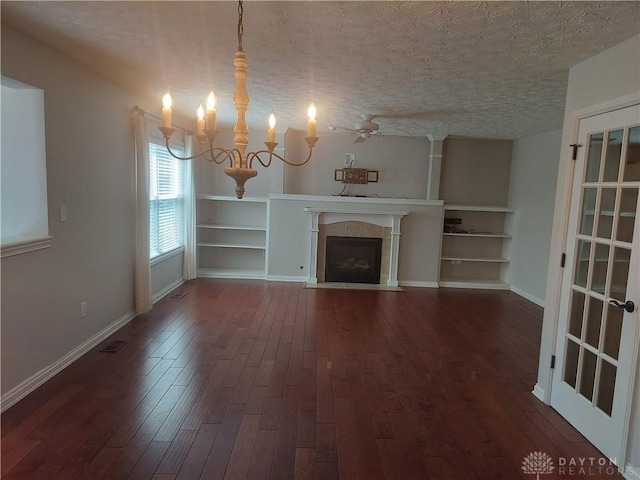 1052 Windpointe Way, Englewood, OH 45322 - unfurnished living room with dark wood finished floors, a chandelier, a textured ceiling, built in shelves, and a tiled fireplace