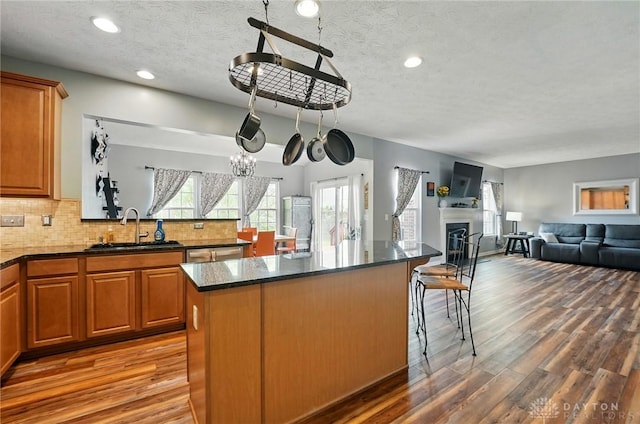 1662 S Branch Rd, Centerville, OH 45458 - kitchen featuring wood finished floors, a textured ceiling, backsplash, brown cabinets, and a kitchen island