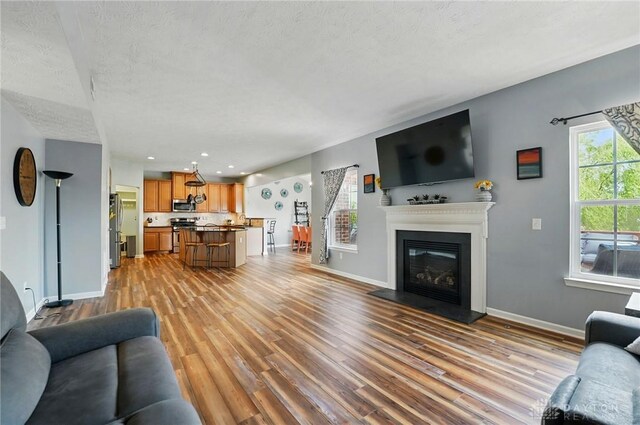 1662 S Branch Rd, Centerville, OH 45458 - living room featuring light wood-type flooring, recessed lighting, a glass covered fireplace, and a textured ceiling