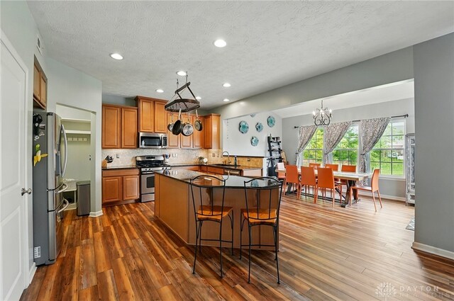 1662 S Branch Rd, Centerville, OH 45458 - kitchen featuring appliances with stainless steel finishes, a chandelier, dark wood finished floors, brown cabinetry, and decorative backsplash