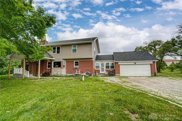 3348 Phillipsburg Union Rd, Englewood, OH 45322 - rear view of property with driveway, an attached garage, a yard, and brick siding
