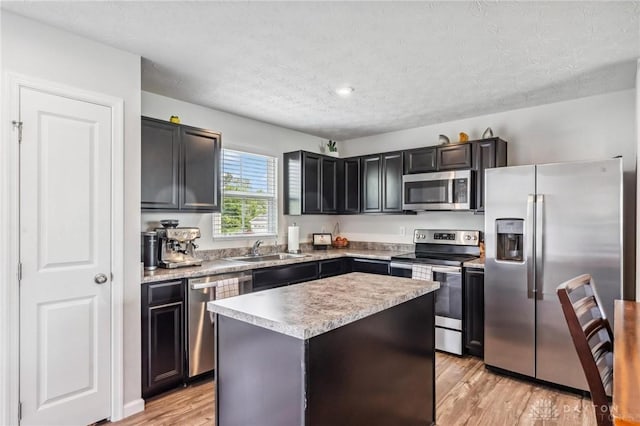 1918 Bessie Ave, Moraine, OH 45439 - kitchen featuring appliances with stainless steel finishes, a textured ceiling, light wood finished floors, a center island, and light countertops