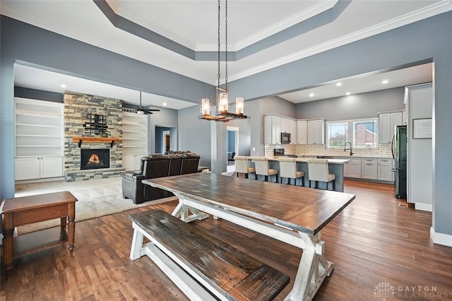 1584 Heritage Run Dr, Lebanon, OH 45036 - dining area featuring wood finished floors, a raised ceiling, a fireplace, ornamental molding, and a chandelier