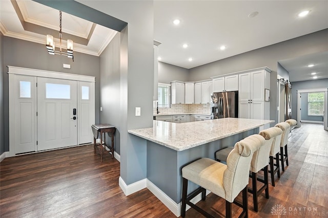 1584 Heritage Run Dr, Lebanon, OH 45036 - kitchen with stainless steel fridge, a peninsula, ornamental molding, a chandelier, and light stone countertops