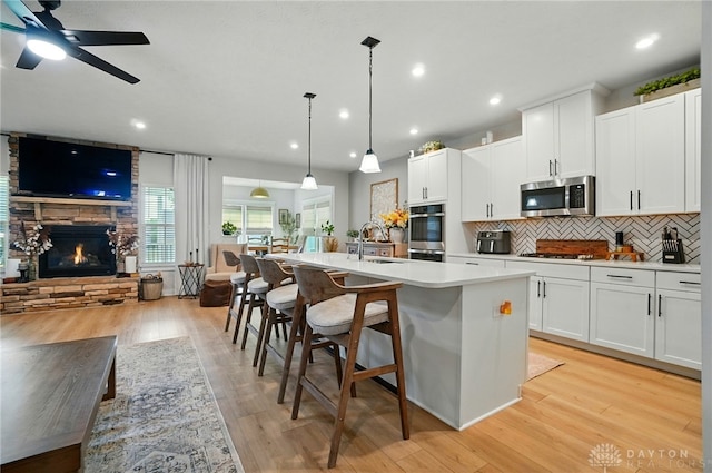 181 Cresting Rd, Fairborn, OH 45324 - kitchen with stainless steel appliances, open floor plan, a center island with sink, tasteful backsplash, and a fireplace