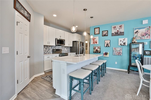 928 Southline Dr, Lebanon, OH 45036 - kitchen with appliances with stainless steel finishes, a breakfast bar area, light countertops, a kitchen island with sink, and decorative backsplash