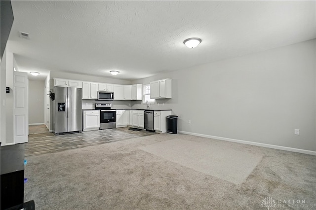 720 Diamond Loop, Middletown, OH 45044 - kitchen with stainless steel appliances, white cabinets, light colored carpet, open floor plan, and a textured ceiling