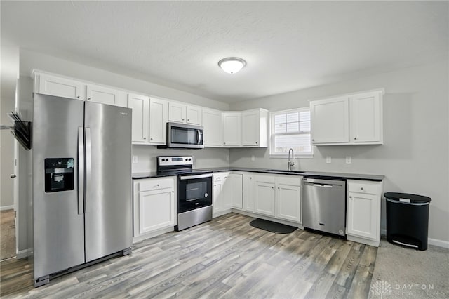 720 Diamond Loop, Middletown, OH 45044 - kitchen with stainless steel appliances, dark countertops, white cabinetry, and light wood-type flooring