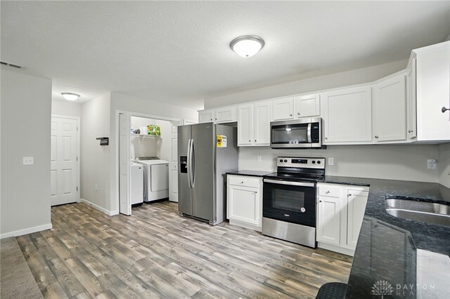 720 Diamond Loop, Middletown, OH 45044 - kitchen with appliances with stainless steel finishes, separate washer and dryer, light wood-style floors, white cabinets, and dark stone counters
