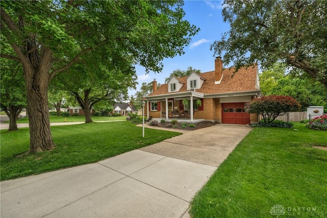 3611 Delaine Ave, Kettering, OH 45429 - cape cod home with covered porch, a front yard, a chimney, concrete driveway, and brick siding