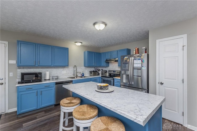 1107 Sunset Dr, Englewood, OH 45322 - kitchen featuring stainless steel appliances, blue cabinetry, under cabinet range hood, dark wood finished floors, and a textured ceiling