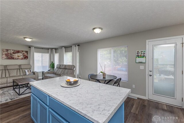 1107 Sunset Dr, Englewood, OH 45322 - kitchen featuring blue cabinets, open floor plan, dark wood finished floors, light countertops, and healthy amount of natural light