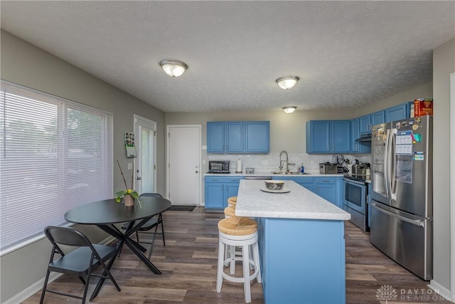 1107 Sunset Dr, Englewood, OH 45322 - kitchen featuring appliances with stainless steel finishes, blue cabinets, dark wood-style floors, light countertops, and a center island