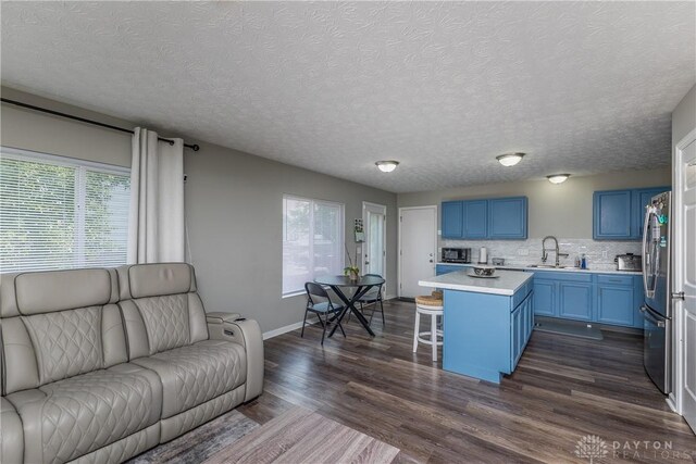 1107 Sunset Dr, Englewood, OH 45322 - kitchen with open floor plan, blue cabinetry, light countertops, a kitchen breakfast bar, and dark wood-type flooring