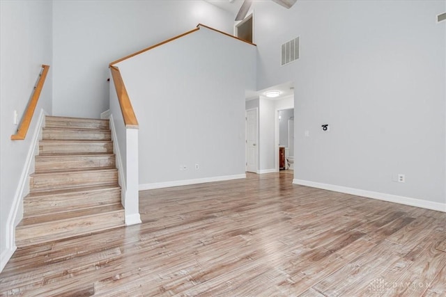 113 Village Trail Dr Unit 6, Vandalia, OH 45377 - unfurnished living room with a towering ceiling, wood finished floors, stairs, and a ceiling fan