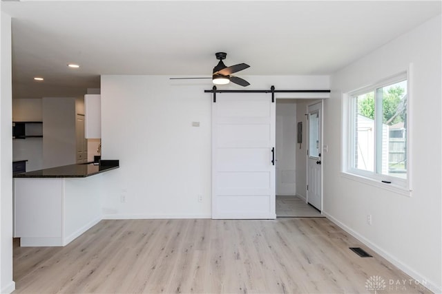 7044 Park Vista Rd, Englewood, OH 45322 - unfurnished living room with a barn door, light wood-type flooring, a ceiling fan, and recessed lighting