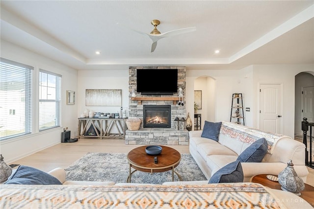 5078 Magellan Way, Franklin, OH 45005 - living area featuring arched walkways, a tray ceiling, a fireplace, wood finished floors, and a ceiling fan