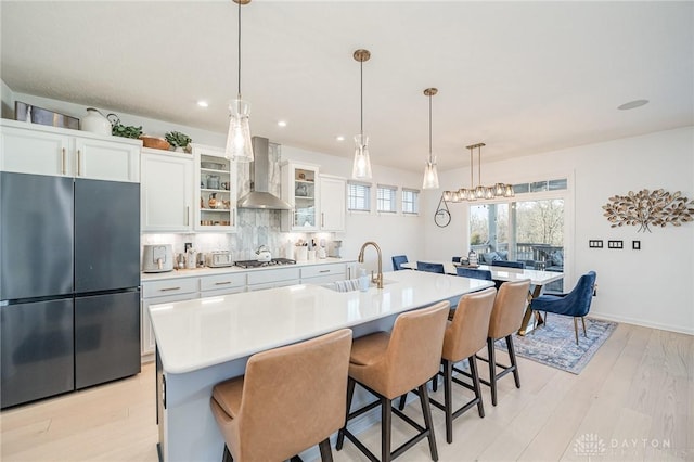 5078 Magellan Way, Franklin, OH 45005 - kitchen with freestanding refrigerator, wall chimney range hood, stainless steel gas cooktop, light countertops, and light wood-type flooring