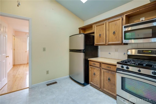 301 E Peach Orchard Ave, Oakwood, OH 45419 - kitchen with appliances with stainless steel finishes, open shelves, vaulted ceiling, tasteful backsplash, and light countertops