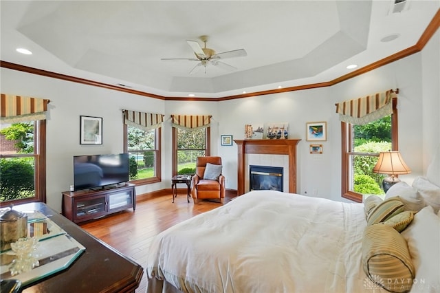 1106 Roger Scott Dr, Bellbrook, OH 45305 - bedroom with multiple windows, wood finished floors, a tray ceiling, ornamental molding, and a tile fireplace