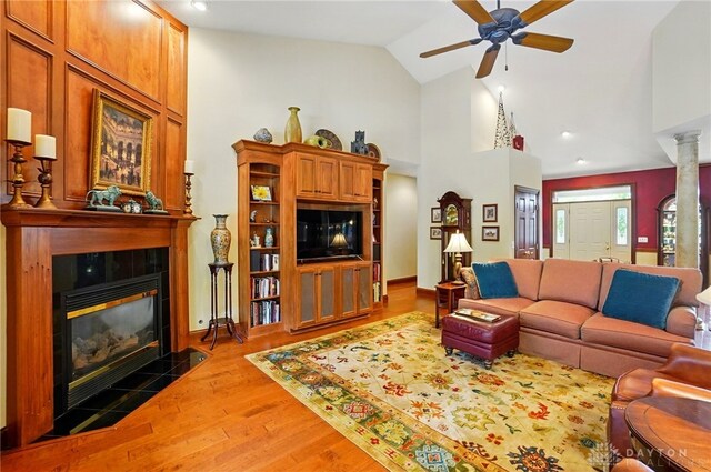 1106 Roger Scott Dr, Bellbrook, OH 45305 - living room featuring a tiled fireplace, a ceiling fan, wood finished floors, and high vaulted ceiling