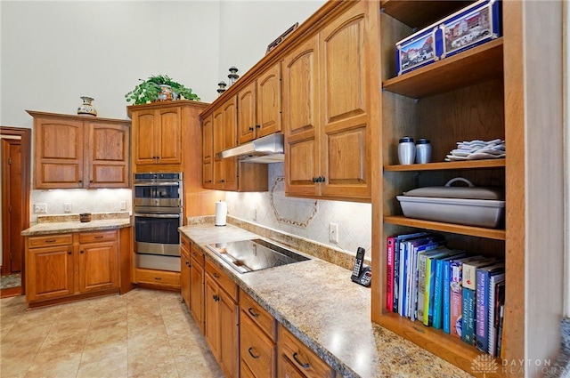 1106 Roger Scott Dr, Bellbrook, OH 45305 - kitchen featuring black electric stovetop, stainless steel double oven, under cabinet range hood, tasteful backsplash, and brown cabinets