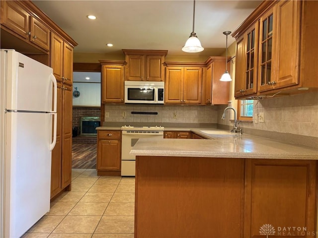 215 W Martindale Rd, Englewood, OH 45322 - kitchen featuring white appliances, a peninsula, brown cabinetry, light countertops, and glass insert cabinets