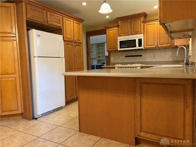 215 W Martindale Rd, Englewood, OH 45322 - kitchen featuring white appliances, tasteful backsplash, brown cabinets, light tile patterned floors, and a peninsula