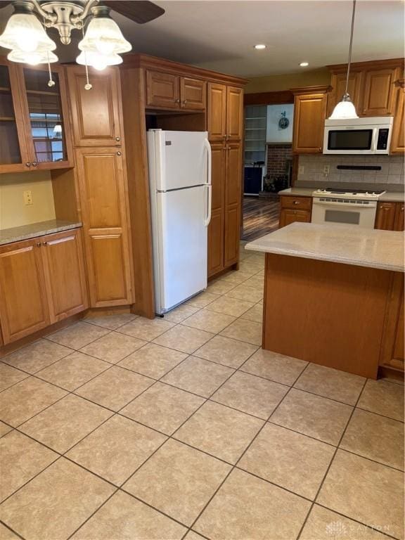 215 W Martindale Rd, Englewood, OH 45322 - kitchen with white appliances, brown cabinetry, tasteful backsplash, hanging light fixtures, and light tile patterned floors