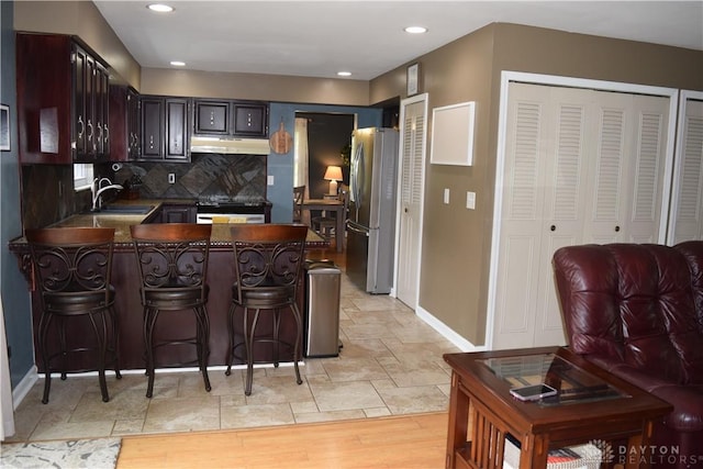 5468 Split Rock Dr, Dayton, OH 45424 - kitchen featuring under cabinet range hood, freestanding refrigerator, a peninsula, oven, and backsplash
