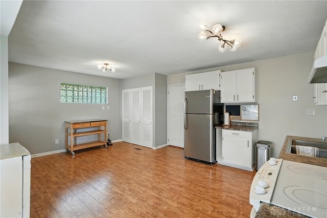 75 Royal Dr, Springboro, OH 45066 - kitchen featuring freestanding refrigerator, stove, light wood finished floors, white cabinetry, and dark countertops